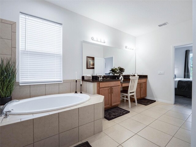 bathroom with vanity, a relaxing tiled tub, and tile patterned flooring