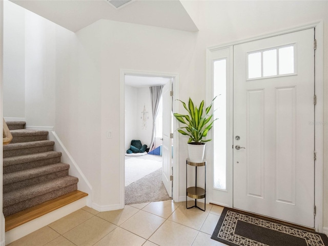 foyer featuring stairs, a healthy amount of sunlight, baseboards, and light tile patterned floors