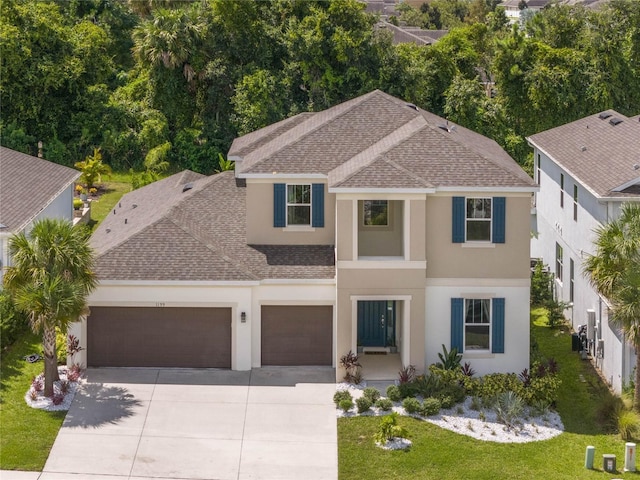 view of front facade with a shingled roof, concrete driveway, a garage, and stucco siding