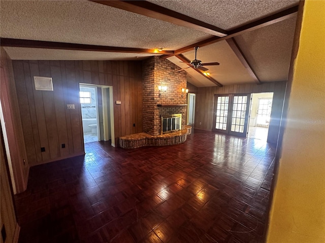 unfurnished living room featuring a fireplace, a textured ceiling, a healthy amount of sunlight, and brick wall