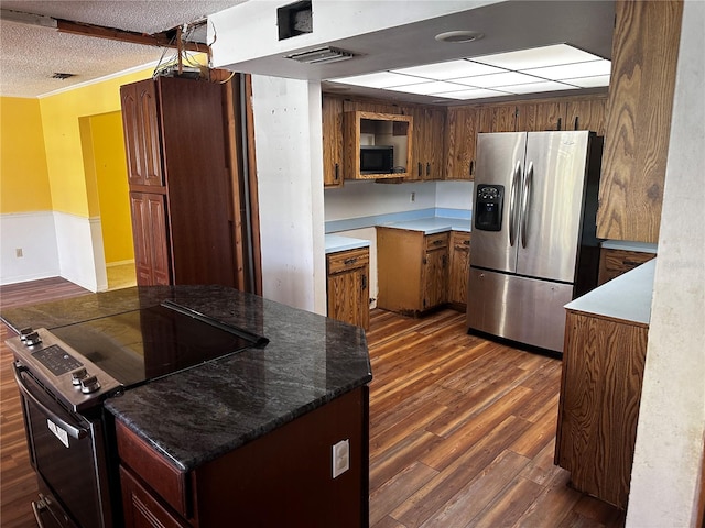 kitchen featuring appliances with stainless steel finishes, dark wood-type flooring, a textured ceiling, and stone counters