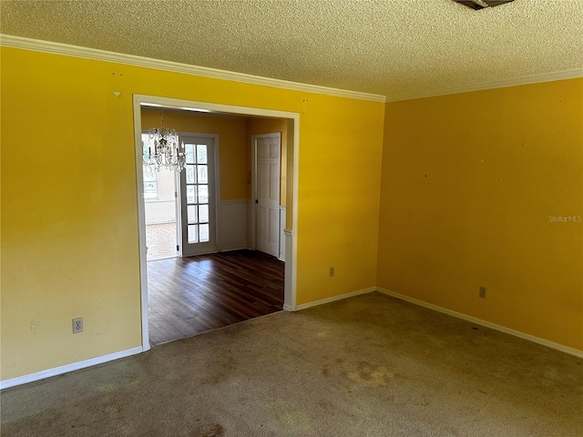 carpeted empty room with a textured ceiling, ornamental molding, and an inviting chandelier