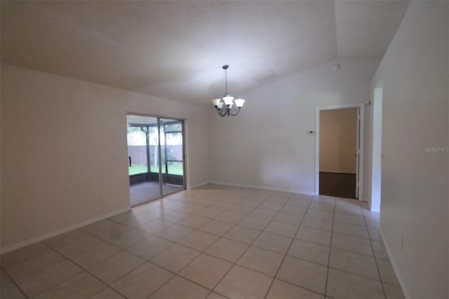 empty room with a notable chandelier, lofted ceiling, and light tile patterned flooring