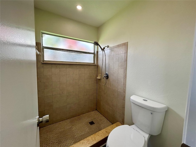 bathroom with a tile shower and toilet