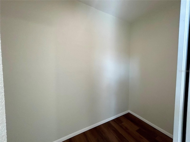 unfurnished room with baseboards and dark wood finished floors