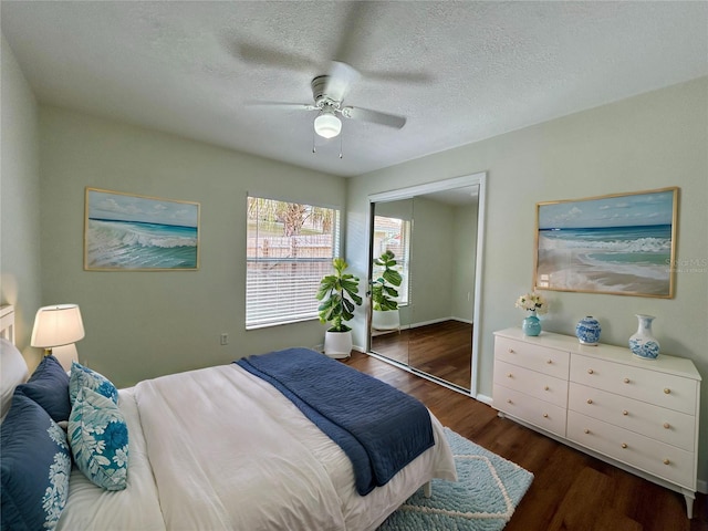 bedroom featuring a textured ceiling, wood finished floors, a closet, baseboards, and ceiling fan