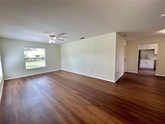 empty room with visible vents, dark wood-type flooring, ceiling fan, and a textured ceiling