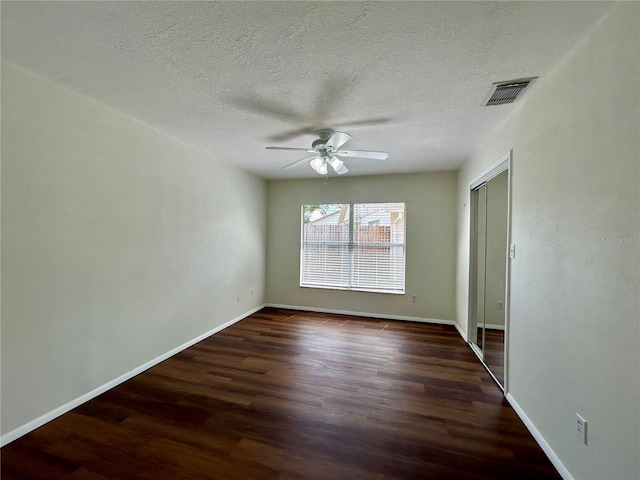 empty room with visible vents, baseboards, dark wood-type flooring, and a ceiling fan