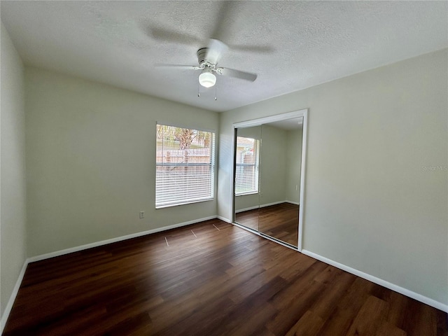 unfurnished bedroom featuring a textured ceiling, wood finished floors, a closet, and baseboards