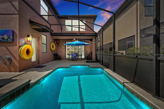 pool at dusk with a patio area and a lanai