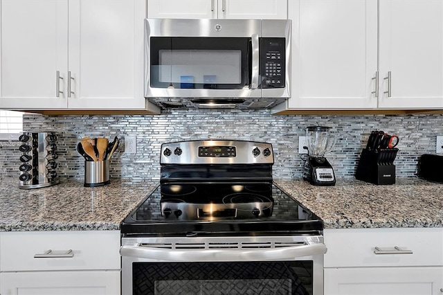 kitchen with stone countertops, stainless steel appliances, white cabinets, and tasteful backsplash