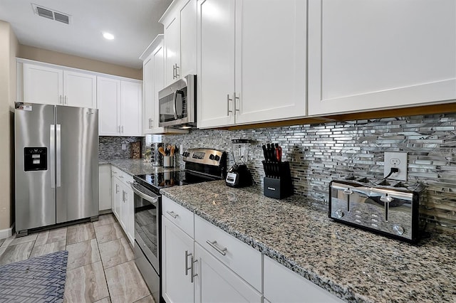 kitchen featuring visible vents, stone countertops, white cabinetry, appliances with stainless steel finishes, and decorative backsplash