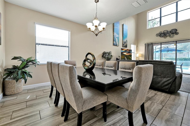 dining space with wood tiled floor, baseboards, visible vents, and a chandelier