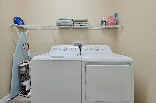 clothes washing area with laundry area, washer and dryer, and baseboards