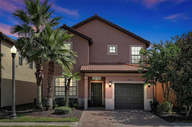 view of front of home featuring stucco siding, decorative driveway, a garage, and a tile roof