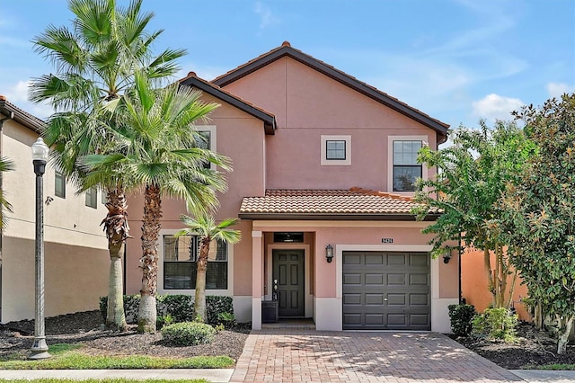 view of front of house with stucco siding, decorative driveway, a garage, and a tiled roof