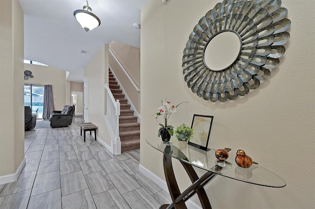 entryway with stairs, visible vents, and baseboards