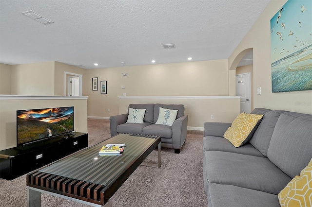 carpeted living area with arched walkways, visible vents, and a textured ceiling