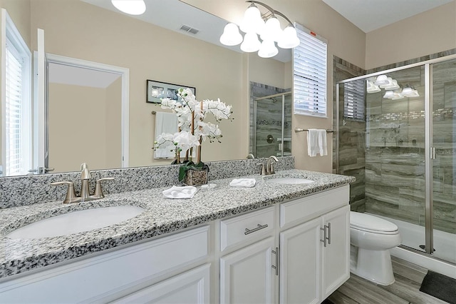 full bath featuring double vanity, visible vents, a stall shower, and a sink