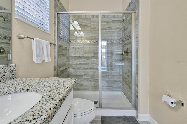 bathroom with a shower with door, vanity, and toilet