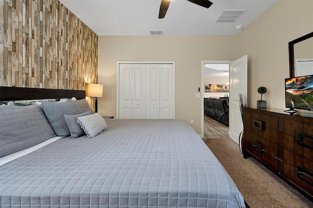 bedroom featuring ceiling fan, wooden walls, light colored carpet, and a closet