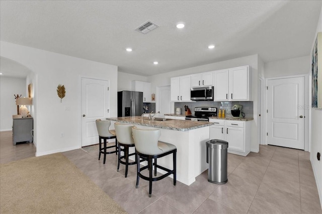 kitchen with a kitchen island with sink, appliances with stainless steel finishes, sink, and white cabinets