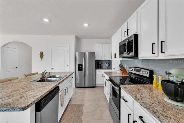 kitchen with backsplash, stainless steel appliances, sink, an island with sink, and light tile patterned floors