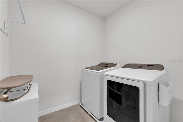 clothes washing area featuring washing machine and dryer and light tile patterned floors