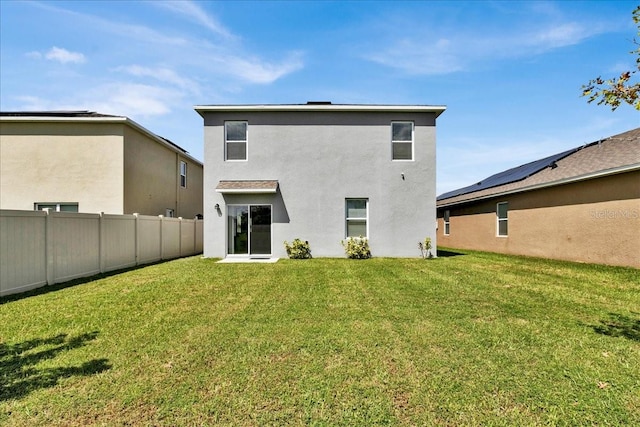 back of house with solar panels and a yard