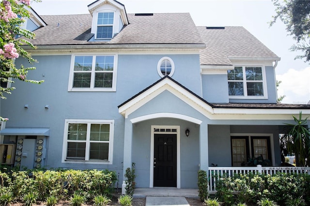 view of front of home with stucco siding, a porch, and a shingled roof