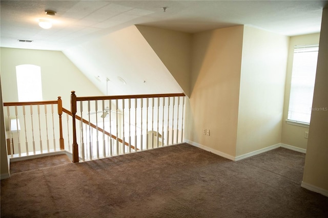 hallway with baseboards, lofted ceiling, and carpet