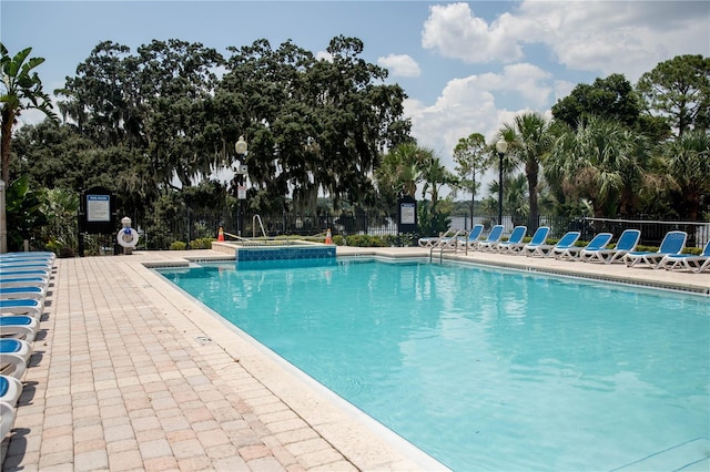 community pool with a patio area and fence