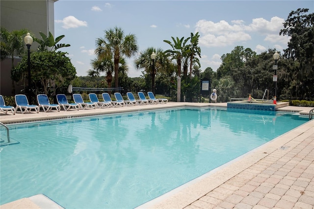 community pool with a patio area and fence