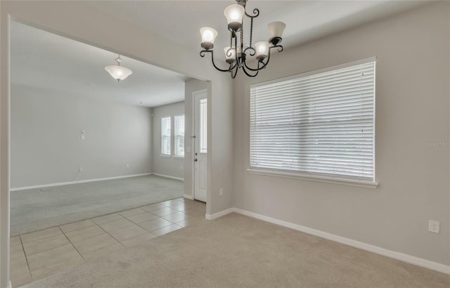 empty room featuring a chandelier and light carpet