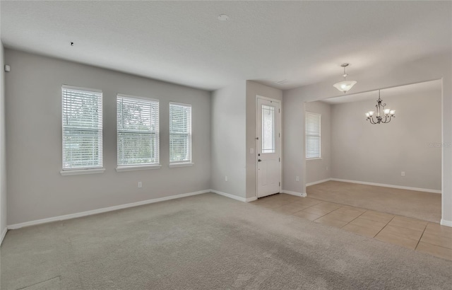 unfurnished room featuring a notable chandelier, light carpet, and a healthy amount of sunlight