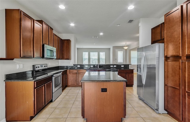 kitchen featuring light tile patterned floors, a center island, stainless steel appliances, and sink