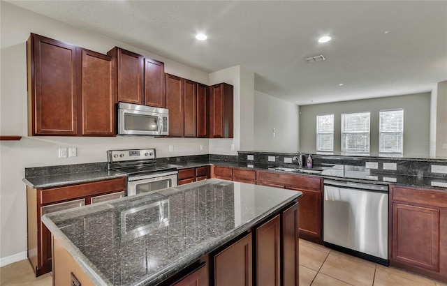 kitchen with light tile patterned flooring, appliances with stainless steel finishes, sink, and dark stone counters