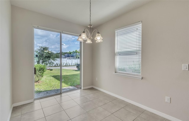 tiled empty room featuring a wealth of natural light and a chandelier