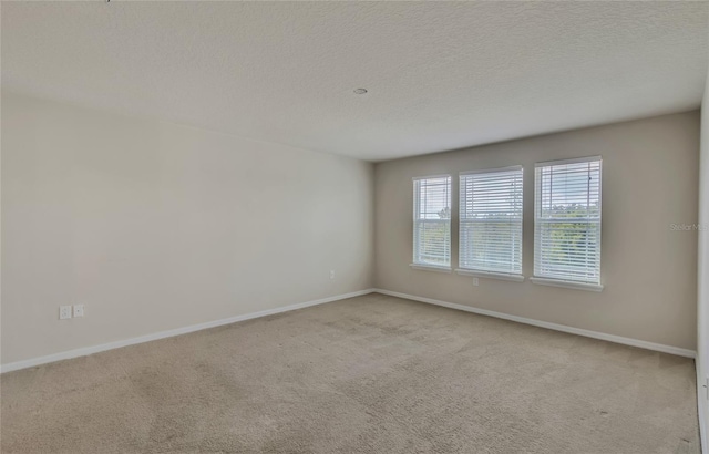 spare room featuring light colored carpet and a textured ceiling