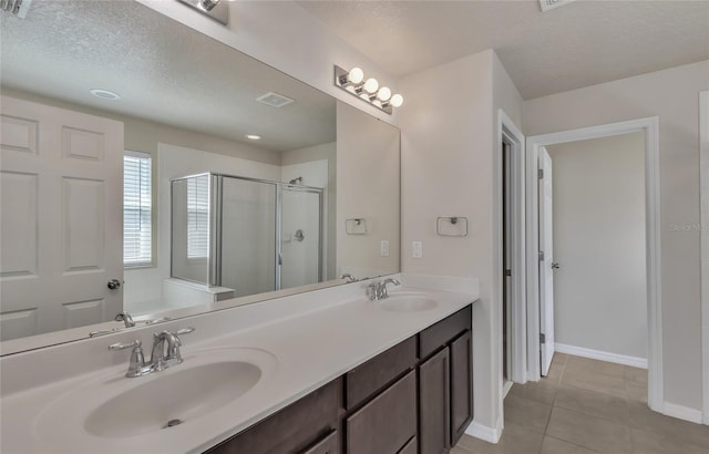 bathroom featuring a shower with door, tile patterned flooring, a textured ceiling, and vanity