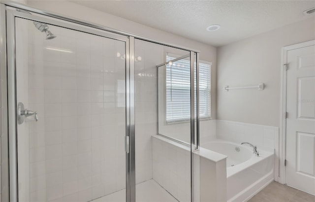 bathroom with shower with separate bathtub, a textured ceiling, and tile patterned flooring