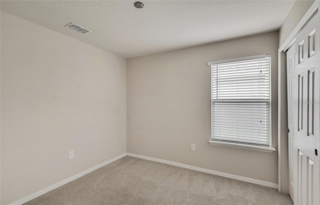 carpeted empty room featuring a textured ceiling