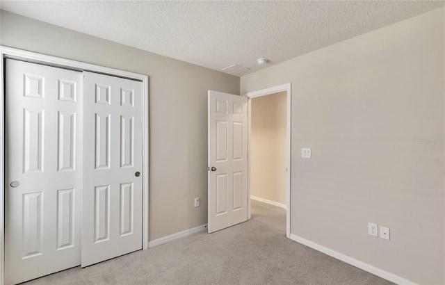 unfurnished bedroom featuring a textured ceiling, a closet, and light carpet