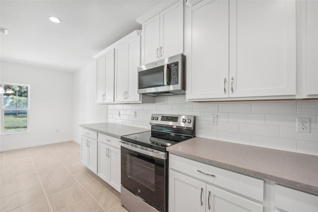 kitchen with backsplash, stainless steel appliances, light tile patterned floors, and white cabinets