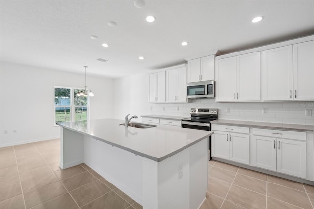 kitchen featuring white cabinetry, stainless steel appliances, a center island with sink, and pendant lighting