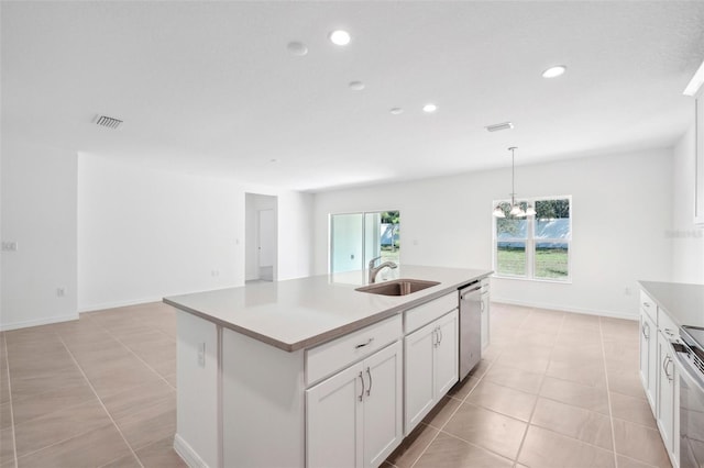 kitchen with a kitchen island with sink, stainless steel appliances, sink, decorative light fixtures, and white cabinetry