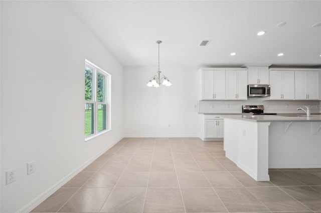 kitchen with stainless steel appliances, pendant lighting, an inviting chandelier, light tile patterned floors, and white cabinetry