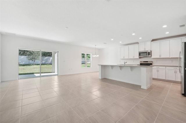 kitchen featuring sink, appliances with stainless steel finishes, light tile patterned flooring, and an island with sink