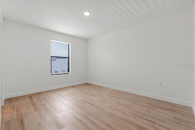 unfurnished room with baseboards and light wood finished floors