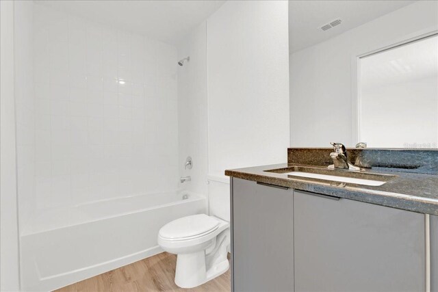 full bathroom with hardwood / wood-style floors, vanity,  shower combination, and toilet